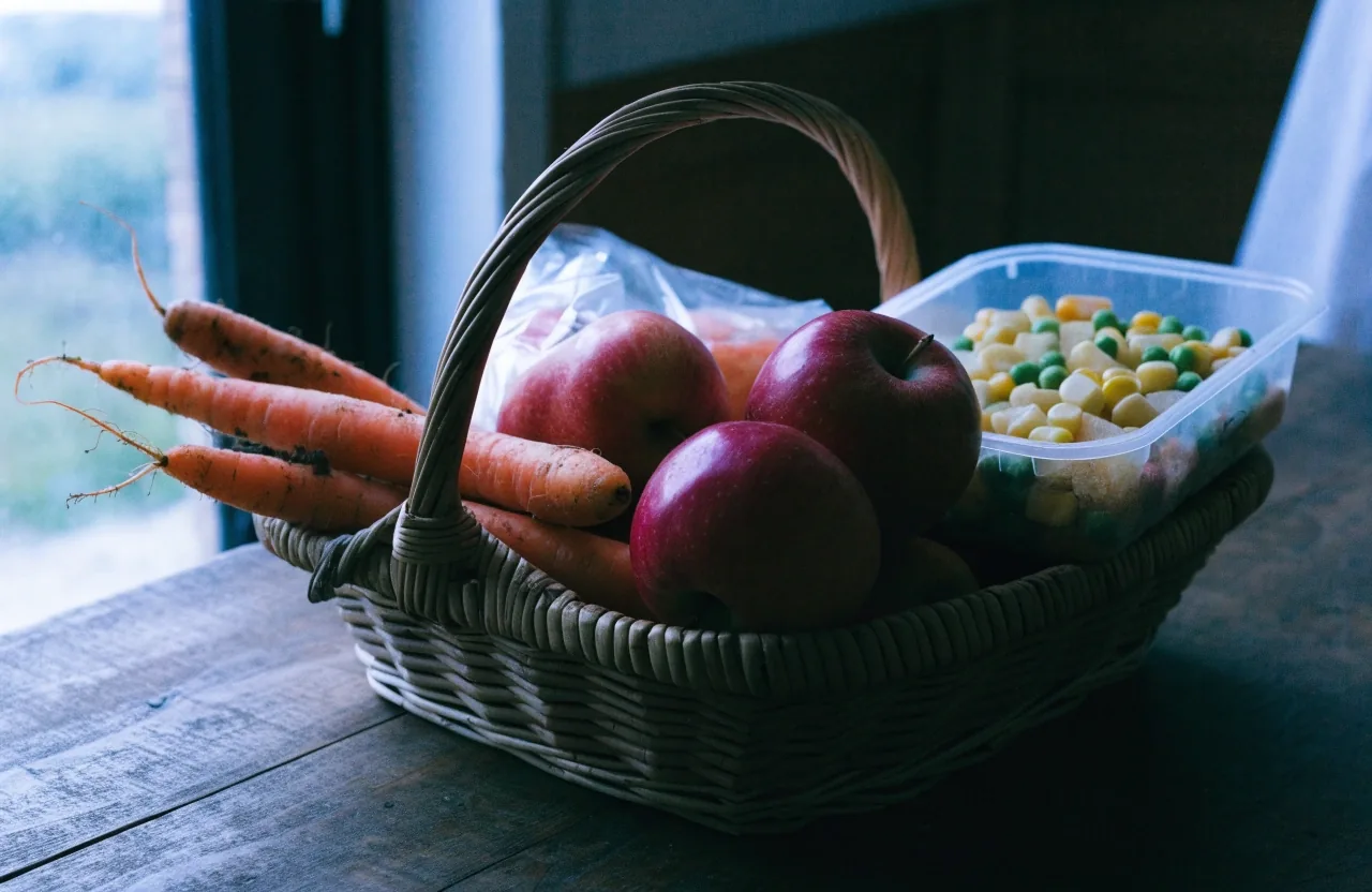 Bol de lentilles et légumes coupés sur un plan de travail sombre éclairé par une seule lampe chaude